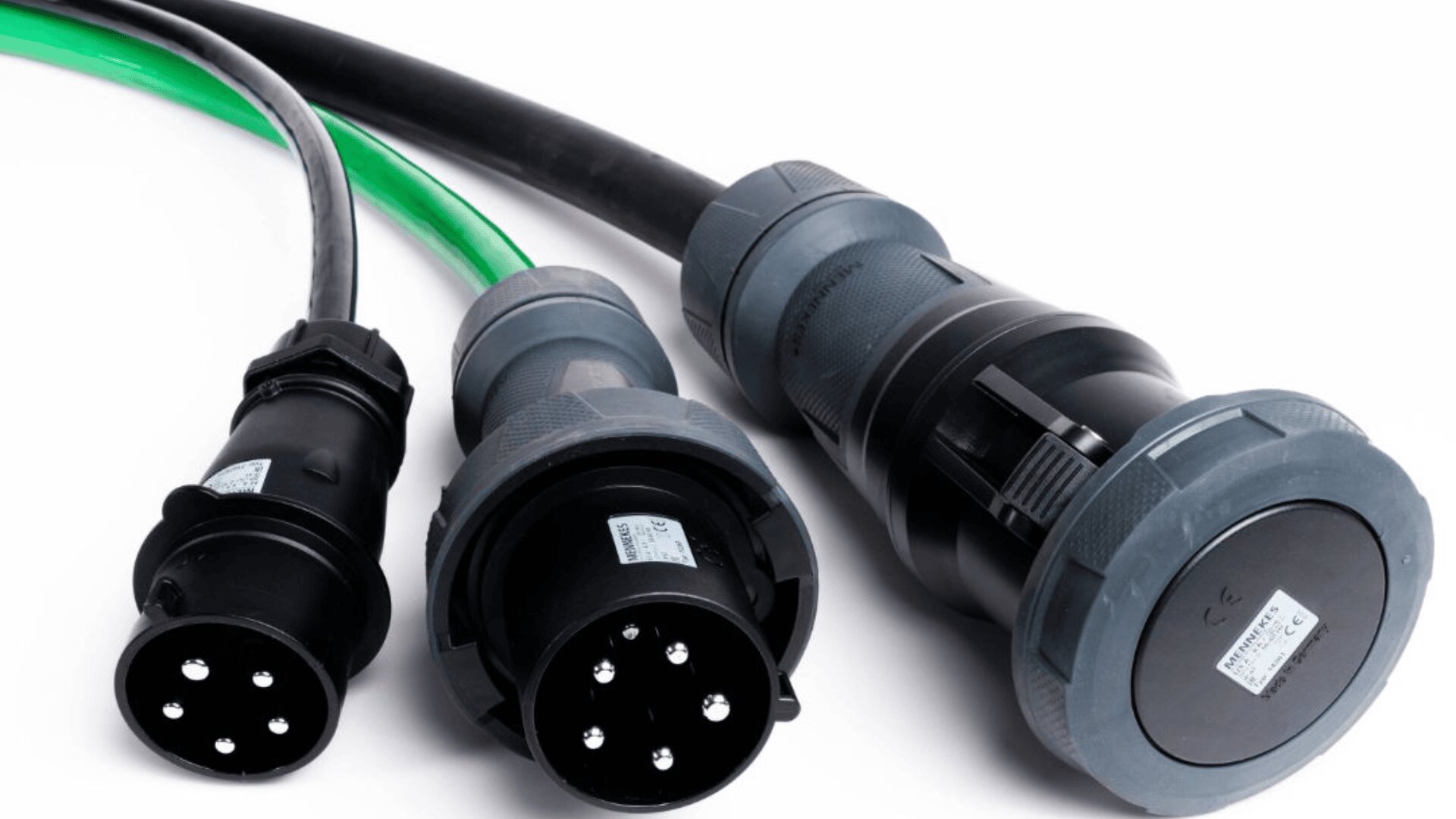 Drei Industriestromstecker mit schwarzen und grünen Kabeln sind vor einem weißen Hintergrund abgebildet. Jeder Stecker hat mehrere Metallstifte und graue oder schwarze Kunststoffgehäuse mit angebrachten Kennzeichnungsschildern.