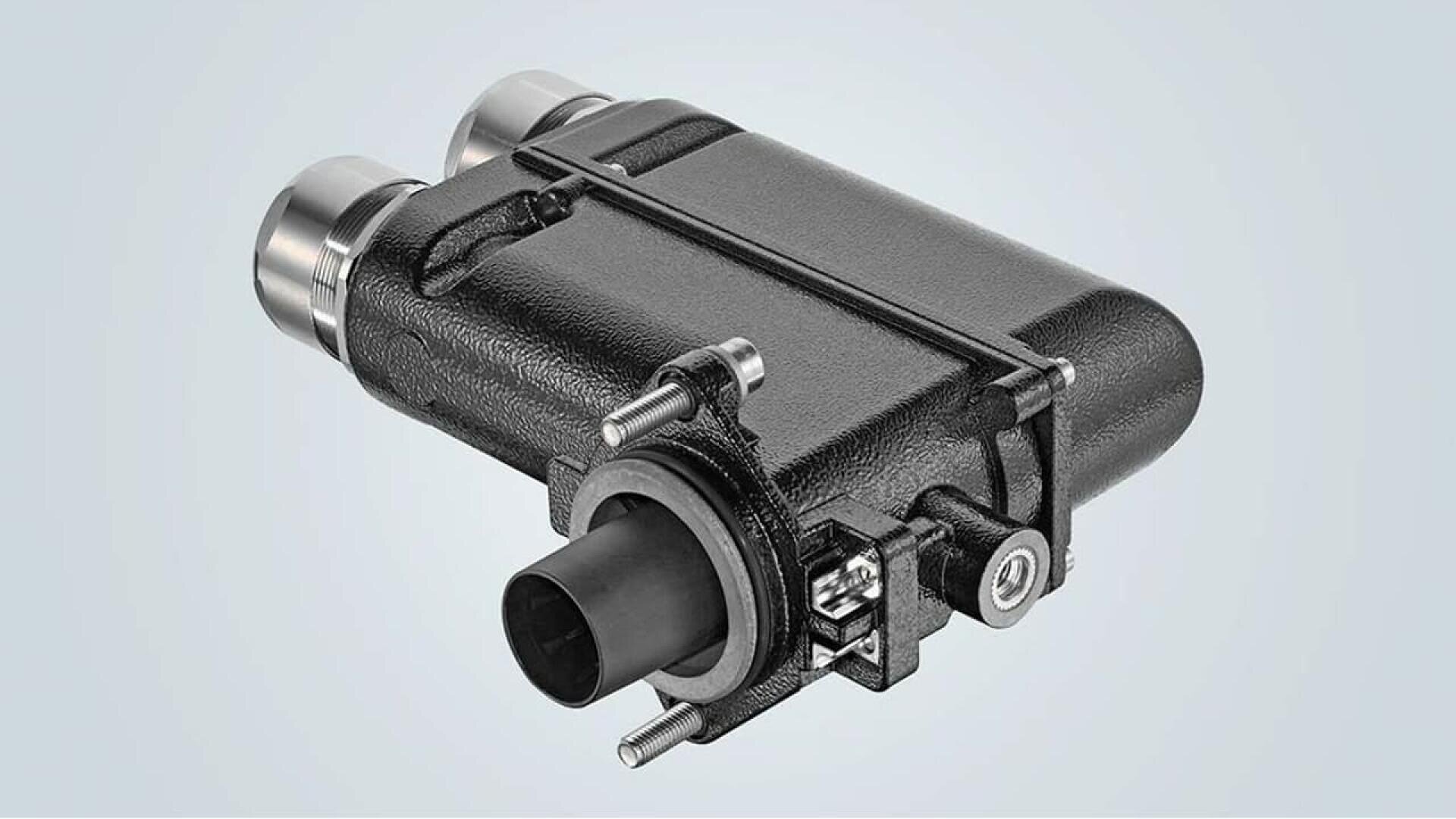 A black, rectangular automotive component with metal connectors and cylindrical attachments, featuring bolts and a protruding nozzle, set against a light gray background.