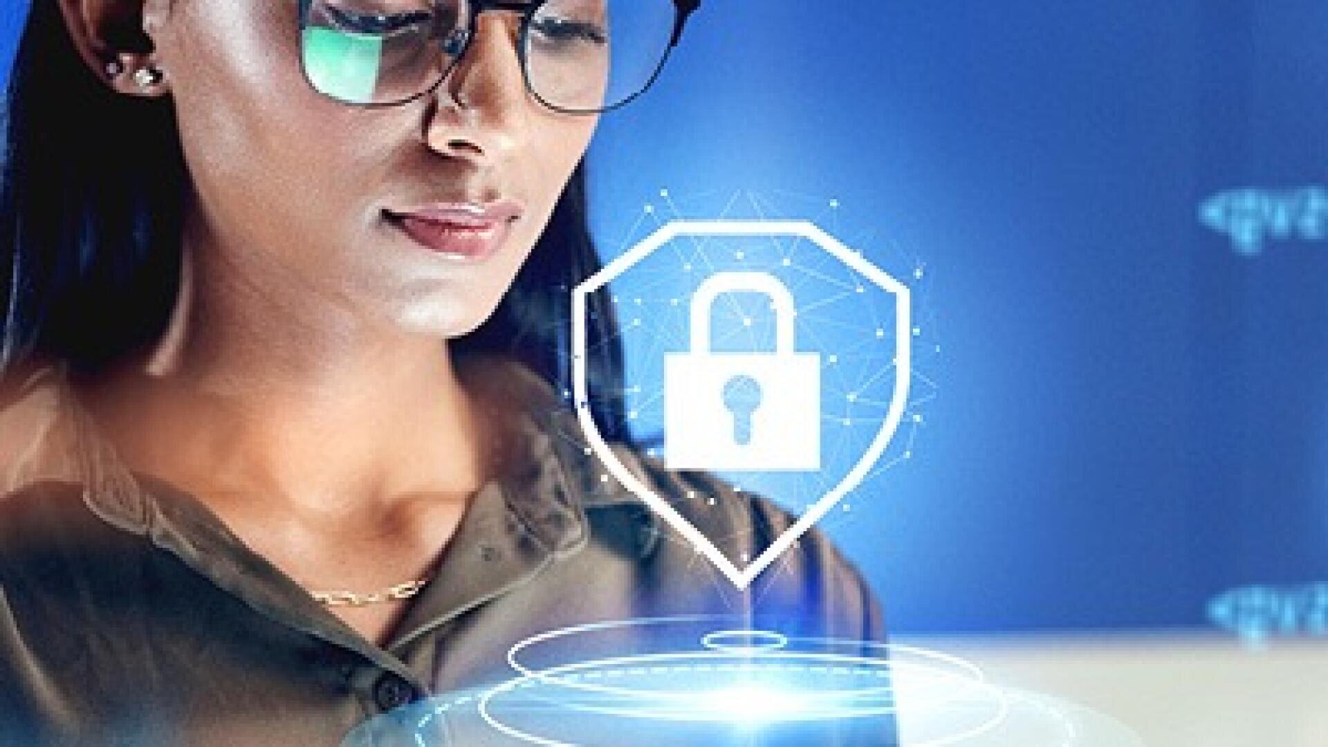Eine Frau mit Brille schaut auf einen Laptop-Bildschirm, auf dem ein digitales Vorhängeschloss und ein Schildsymbol eingeblendet sind, die Cybersicherheit und Datenschutz symbolisieren. Im Hintergrund erscheinen blaue, futuristische Grafiken.