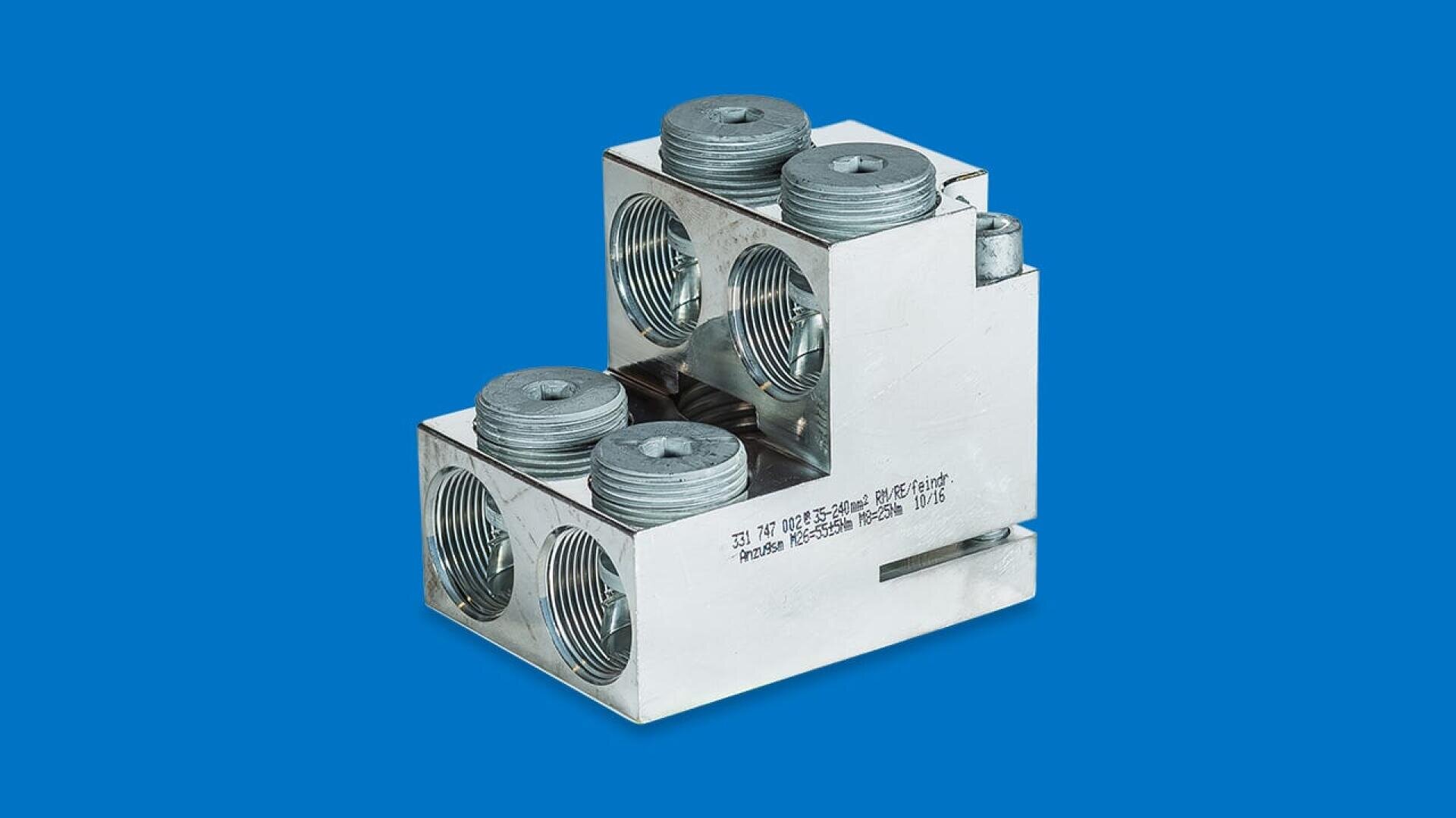 Ein metallisch glänzender elektrischer Anschlussblock mit mehreren großen, kreisförmigen Gewindelöchern und Schrauben vor einem soliden blauen Hintergrund.