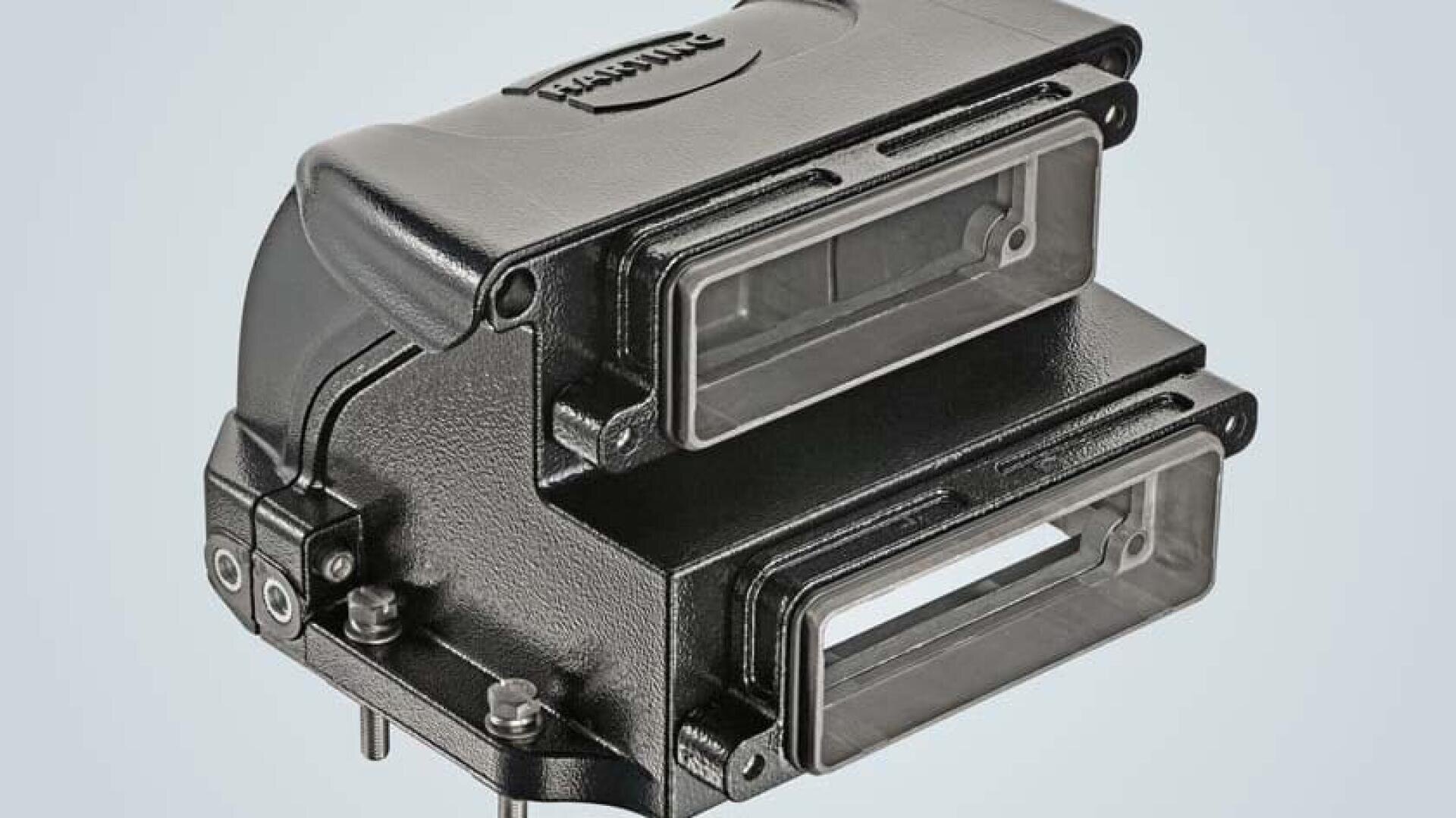 A black, rectangular industrial connector housing with two transparent covers and multiple screws, displayed against a light grey background.
