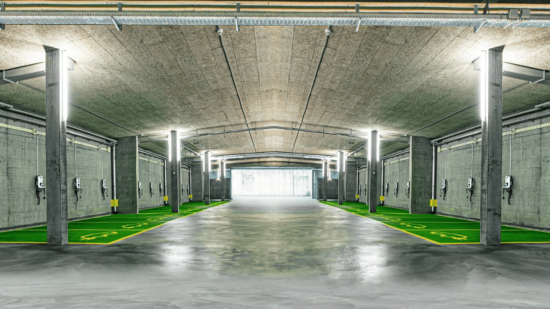 Eine moderne, geräumige Tiefgarage mit grünen Parkplätzen und mehreren Ladestationen für Elektrofahrzeuge entlang der Betonwände, die von Oberlichtern hell erleuchtet werden.