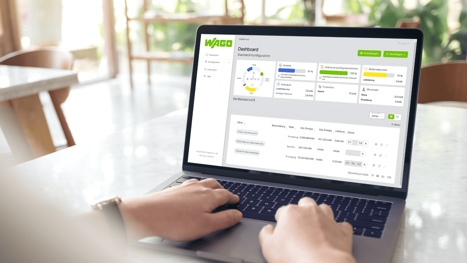 Eine Person benutzt einen Laptop, auf dem ein WAGO-Dashboard mit Diagrammen, Grafiken und Datentabellen angezeigt wird. Auf dem Bildschirm werden Analyse- und Projektmanagement-Tools angezeigt. Die Umgebung scheint ein heller Innenraum mit großen Fenstern zu sein.