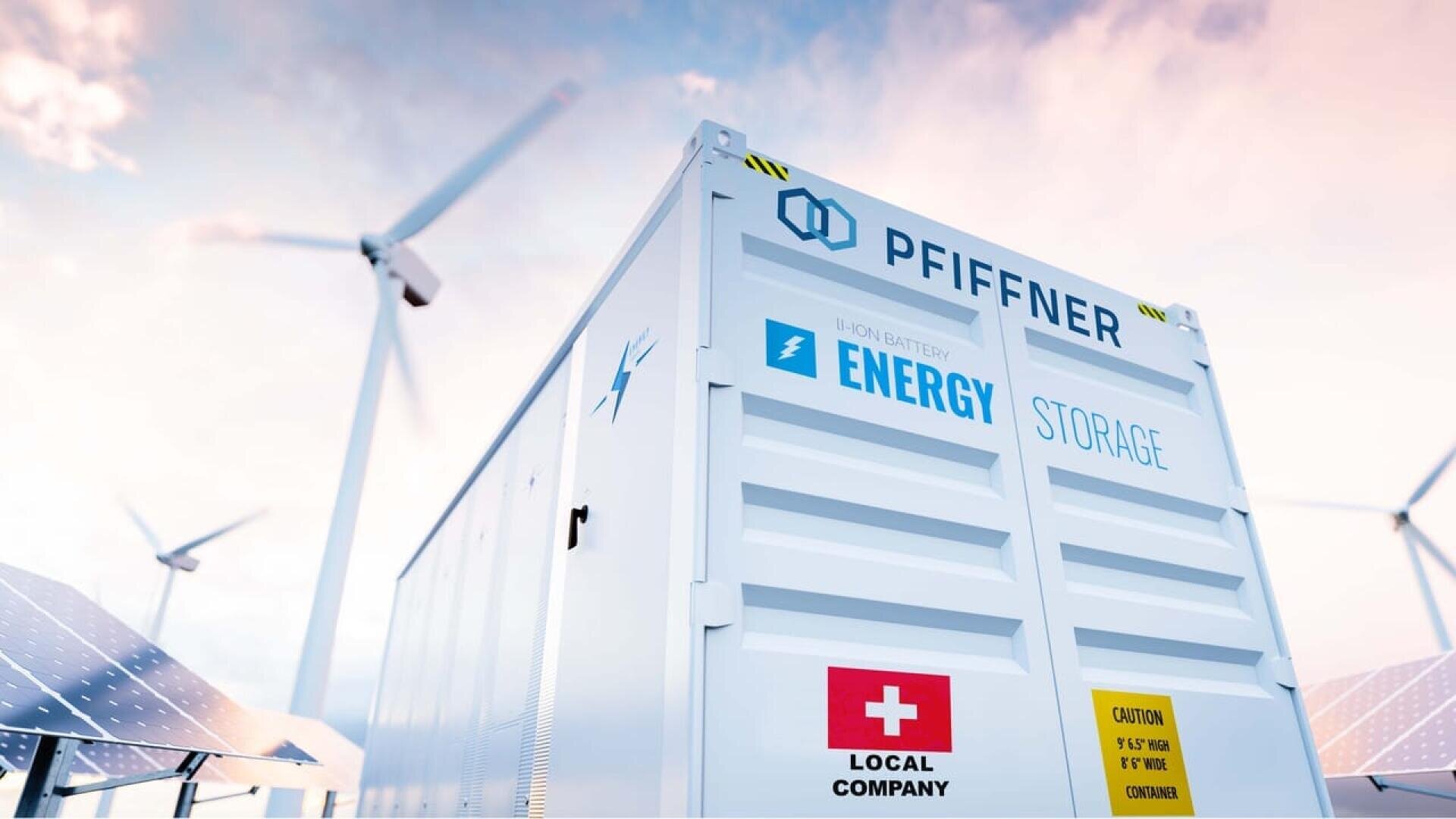 A white energy storage container with company logos stands outdoors, surrounded by solar panels and wind turbines, symbolizing renewable energy and sustainable power solutions. The sky is bright and partly cloudy.