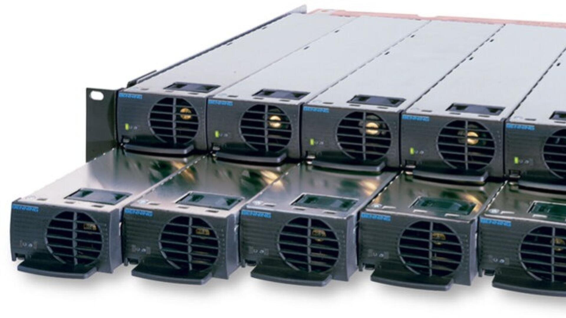 A close-up view of several black power supply units installed in a rack, with each unit featuring a cooling fan and indicator lights on the front panel.
