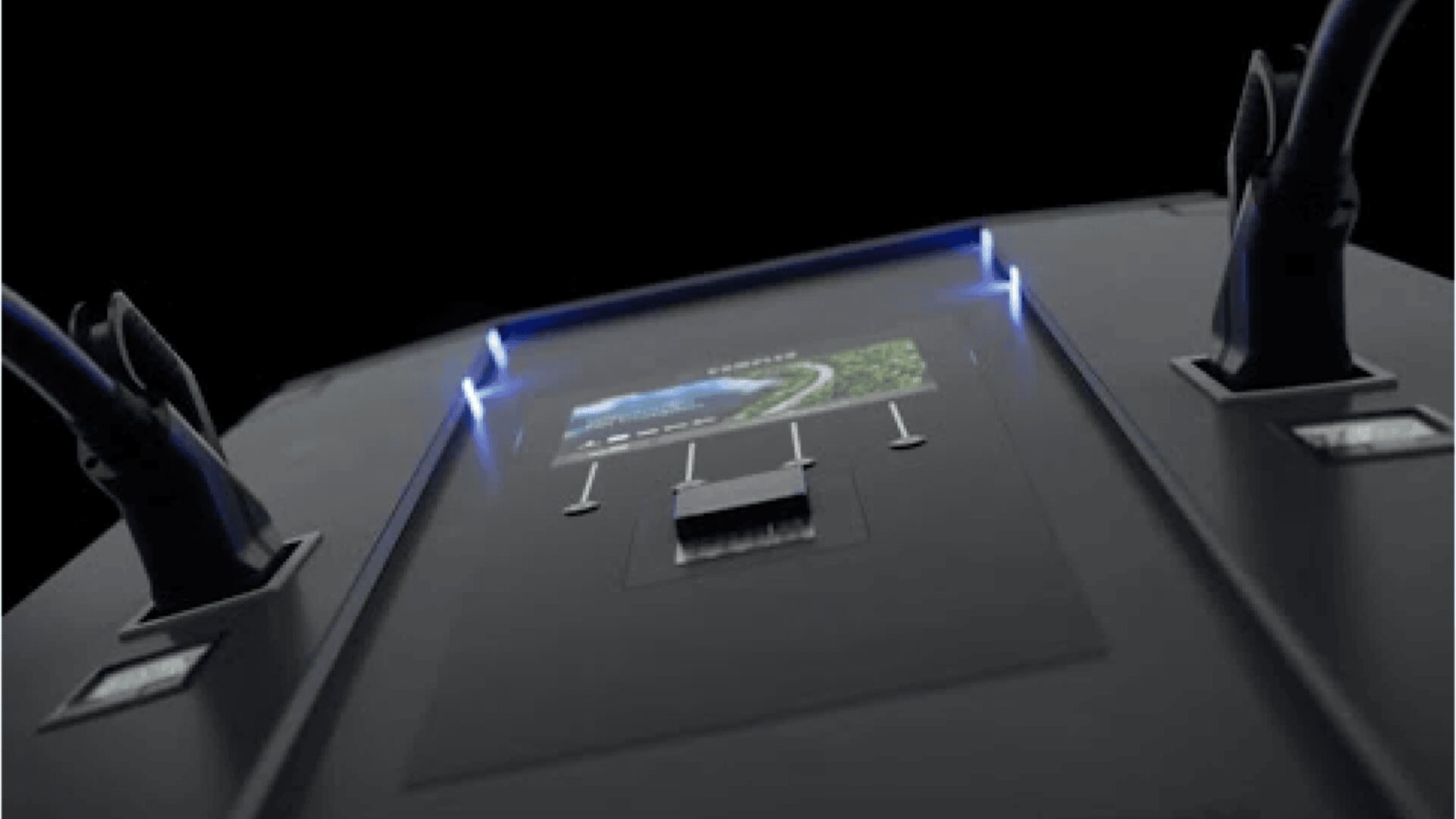 Close-up view of a black electronic device with attached cables, a digital display showing a road, and illuminated blue indicator lights on each side.