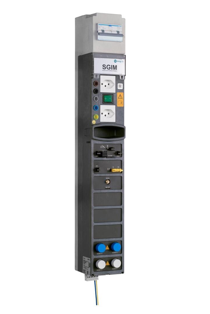 Hohe, rechteckige elektrische Schalttafel mit verschiedenen Schaltern, Steckdosen, Anschlüssen und farbigen Anzeigeleuchten, beschriftet mit "SGIM", vertikal montiert, mit sichtbarer Verdrahtung am Boden.