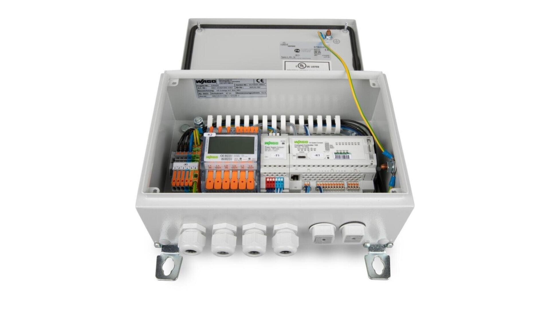 A white electrical control box with an open lid, showing various wiring, terminals, circuit breakers, and control modules neatly organized inside. Four cable glands are visible at the bottom.