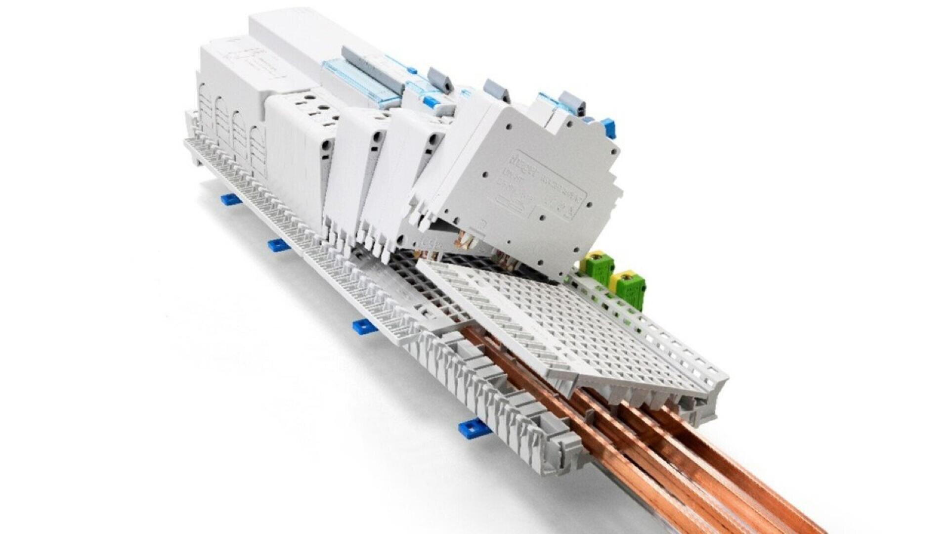 Several white electrical components are mounted on a rail with exposed copper bars under a perforated protective cover, with green and blue terminal blocks visible in the background.