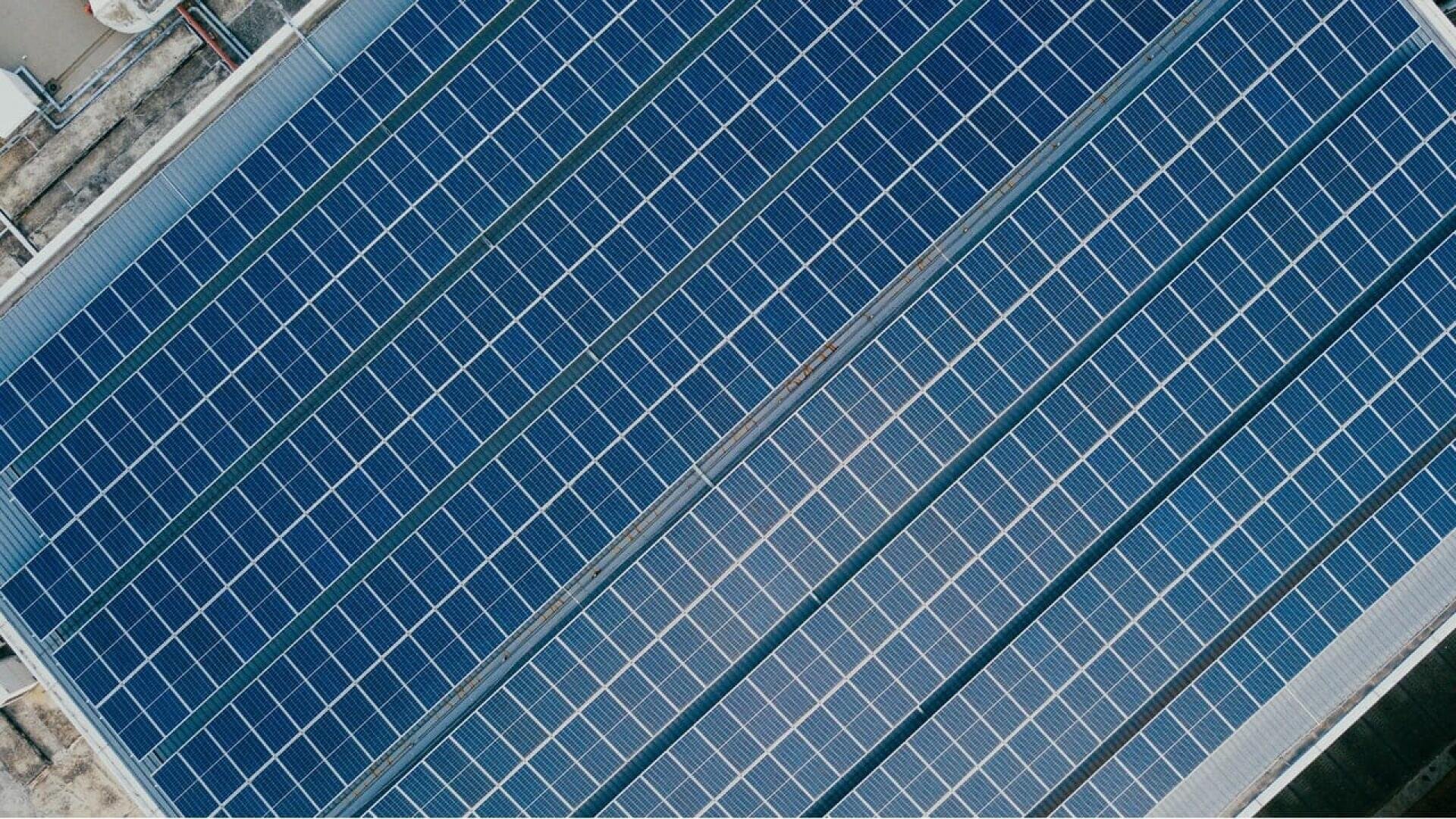 Aerial view of rows of solar panels installed on a rooftop, capturing sunlight for renewable energy generation.