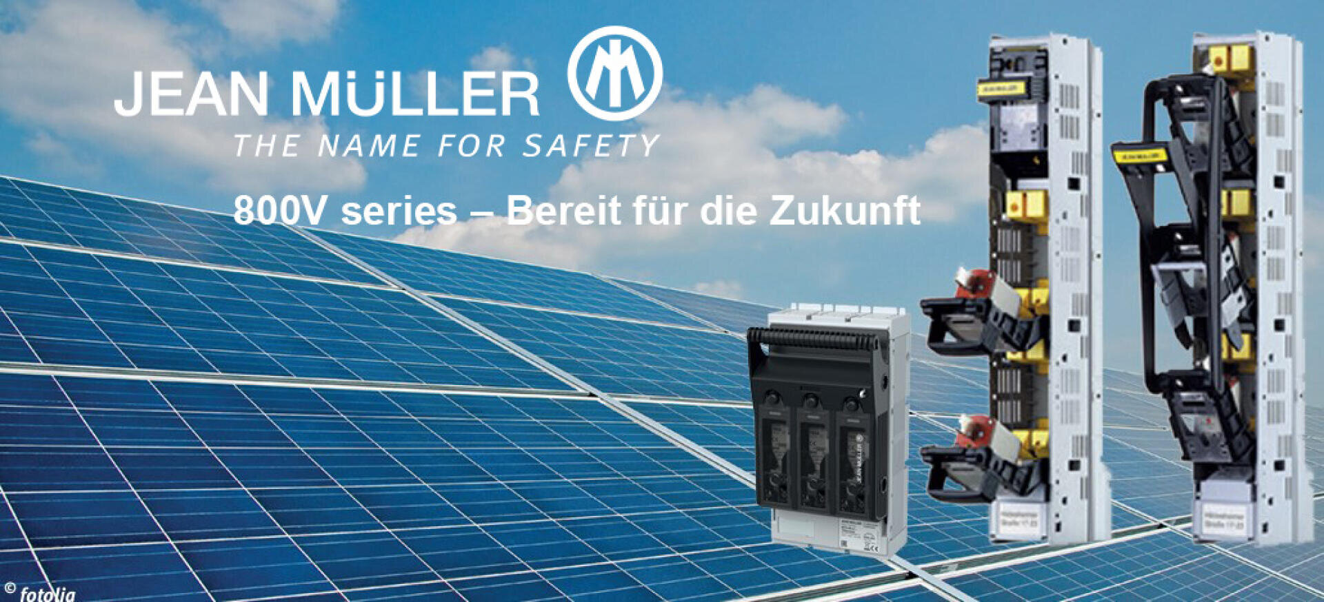 Reihen von Sonnenkollektoren unter blauem Himmel mit elektrischen Sicherheitsgeräten der Marke Jean Müller im Vordergrund. Der Text lautet: JEAN MÜLLER DER NAME FÜR SICHERHEIT. Serie 800V - Bereit für die Zukunft.