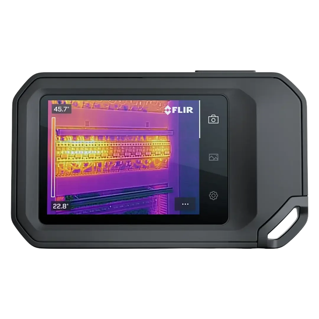 Eine tragbare FLIR-Wärmebildkamera zeigt auf ihrem Bildschirm eine Wärmekarte einer elektrischen Schalttafel an, die verschiedene Temperaturen in Farben von lila bis gelb darstellt.