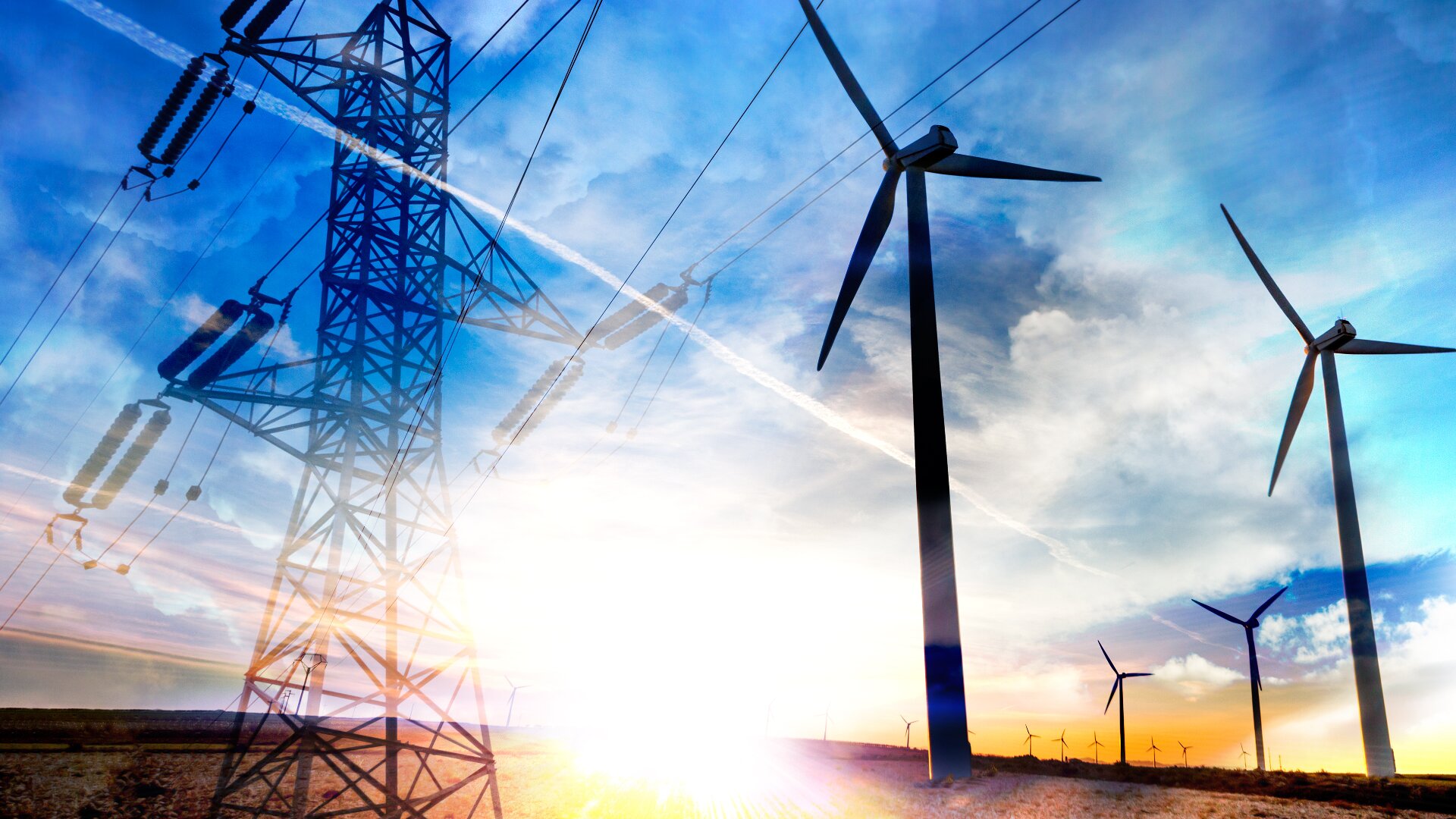 Windturbinen und ein Hochspannungsleitungsmast stehen vor einem hellen, teilweise bewölkten Himmel bei Sonnenuntergang und symbolisieren erneuerbare Energien und Strominfrastruktur in einer ländlichen Landschaft.