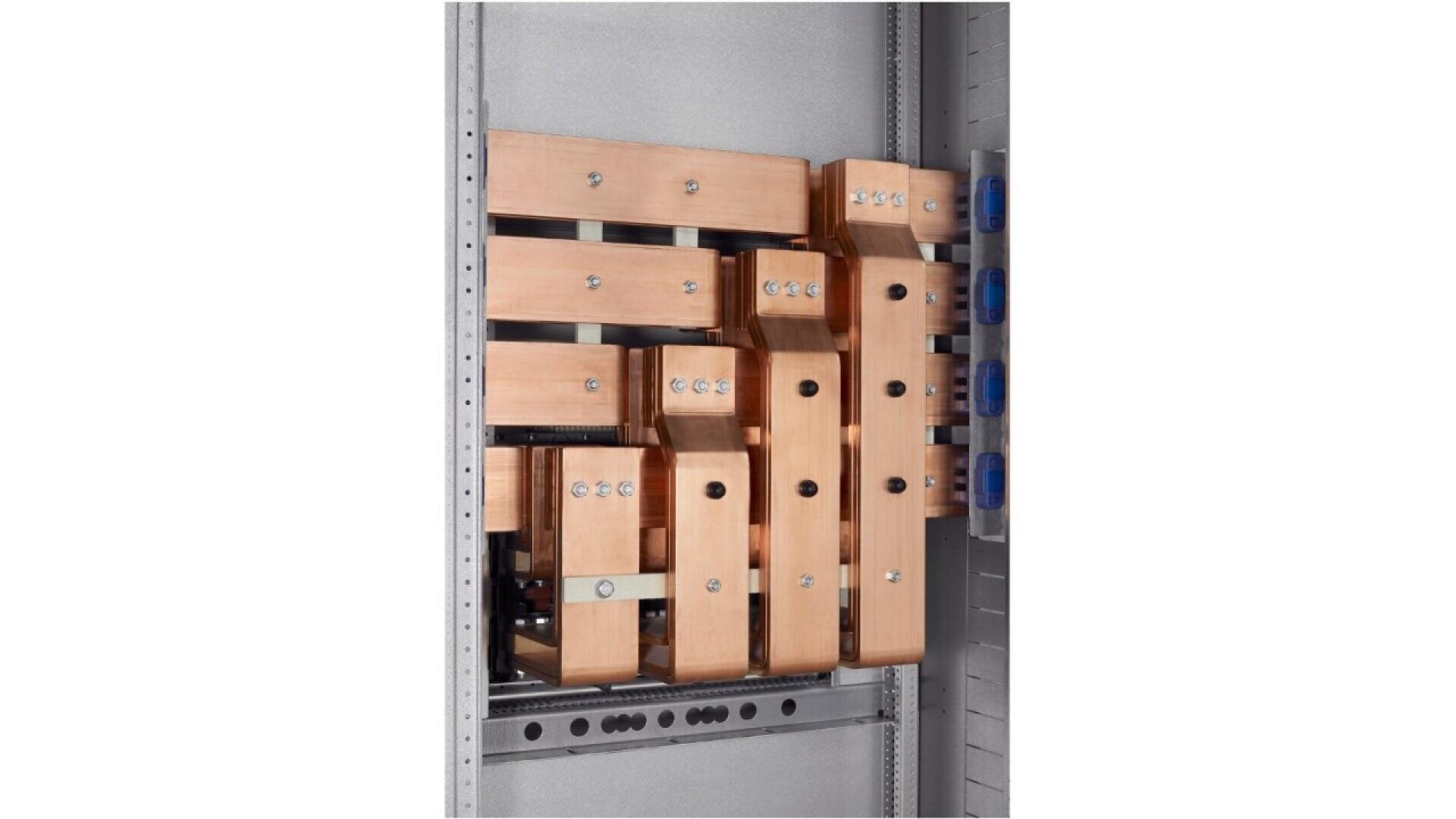 Copper busbars installed vertically in a metal electrical panel, secured with bolts. The busbars are flat, rectangular, and arranged in parallel, used for power distribution within the enclosure.