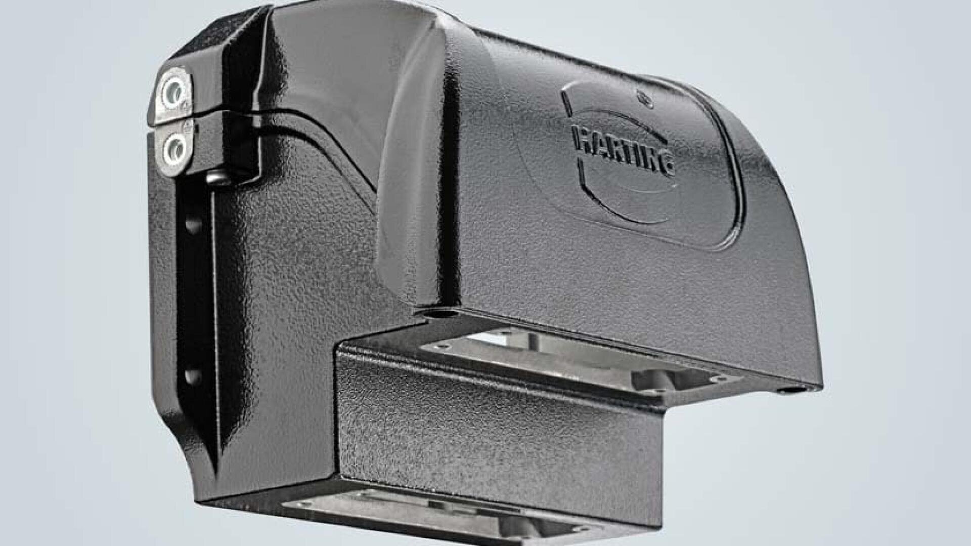 A close-up view of a black industrial connector housing with a metallic finish, showing the HARTING brand name embossed on the top cover. The background is a plain light grey.